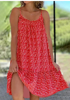 Robe d'été rouge à motifs floraux blancs, sans manches, portée par une femme en extérieur. Mode féminine, tenue estivale décontractée.