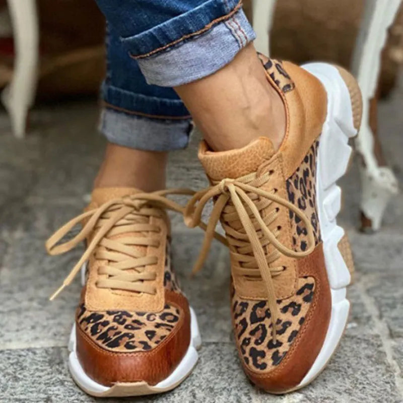 Chaussures de sport léopard pour femme, semelle blanche épaisse, lacets beiges, style décontracté, portées avec un jean retroussé.