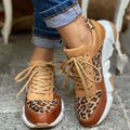 Chaussures de sport léopard pour femme, semelle blanche épaisse, lacets beiges, style décontracté, portées avec un jean retroussé.