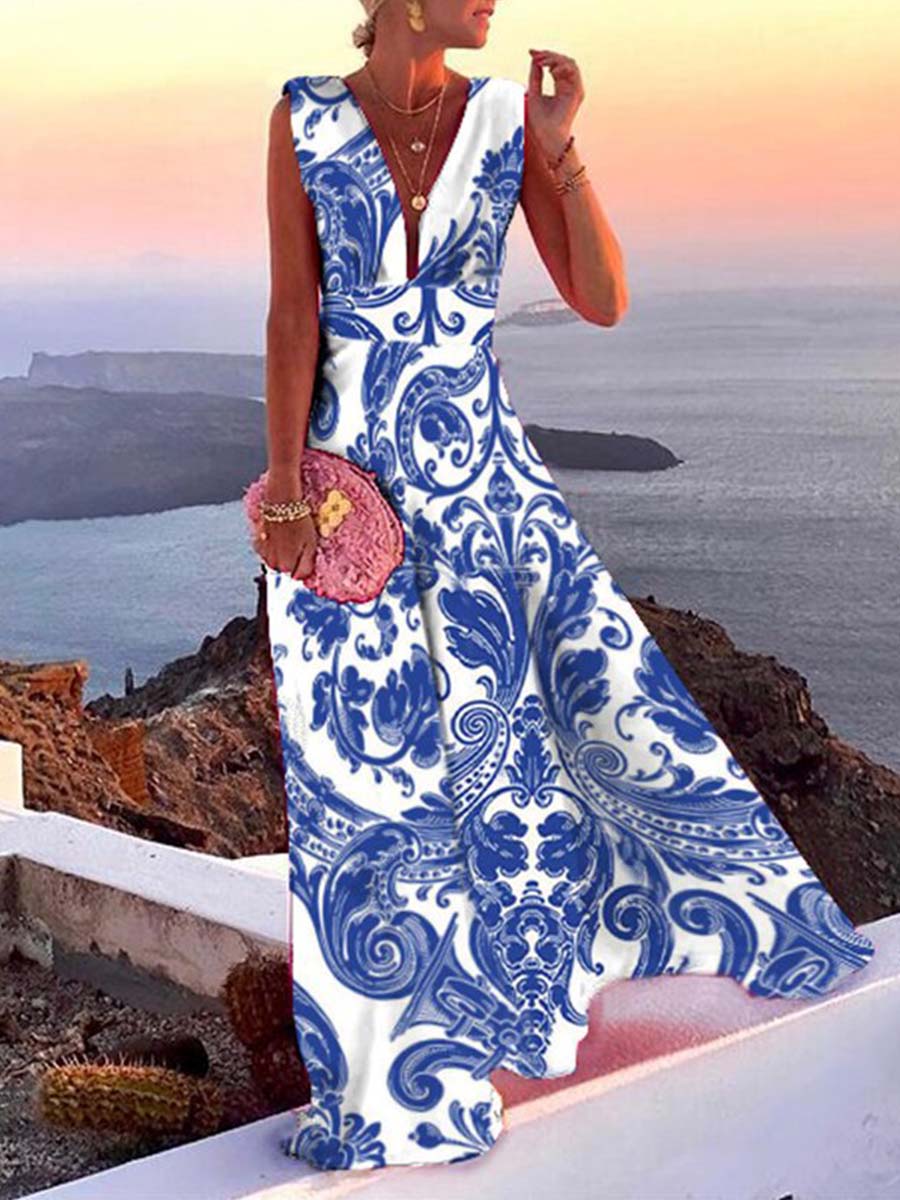 Robe longue élégante à motifs bleus et blancs, femme tenant un sac rose, paysage côtier en arrière-plan, coucher de soleil.