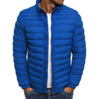 Homme portant une doudoune bleue matelassée, fermeture éclair, col montant, sur un t-shirt blanc. Mode masculine, veste hiver tendance.