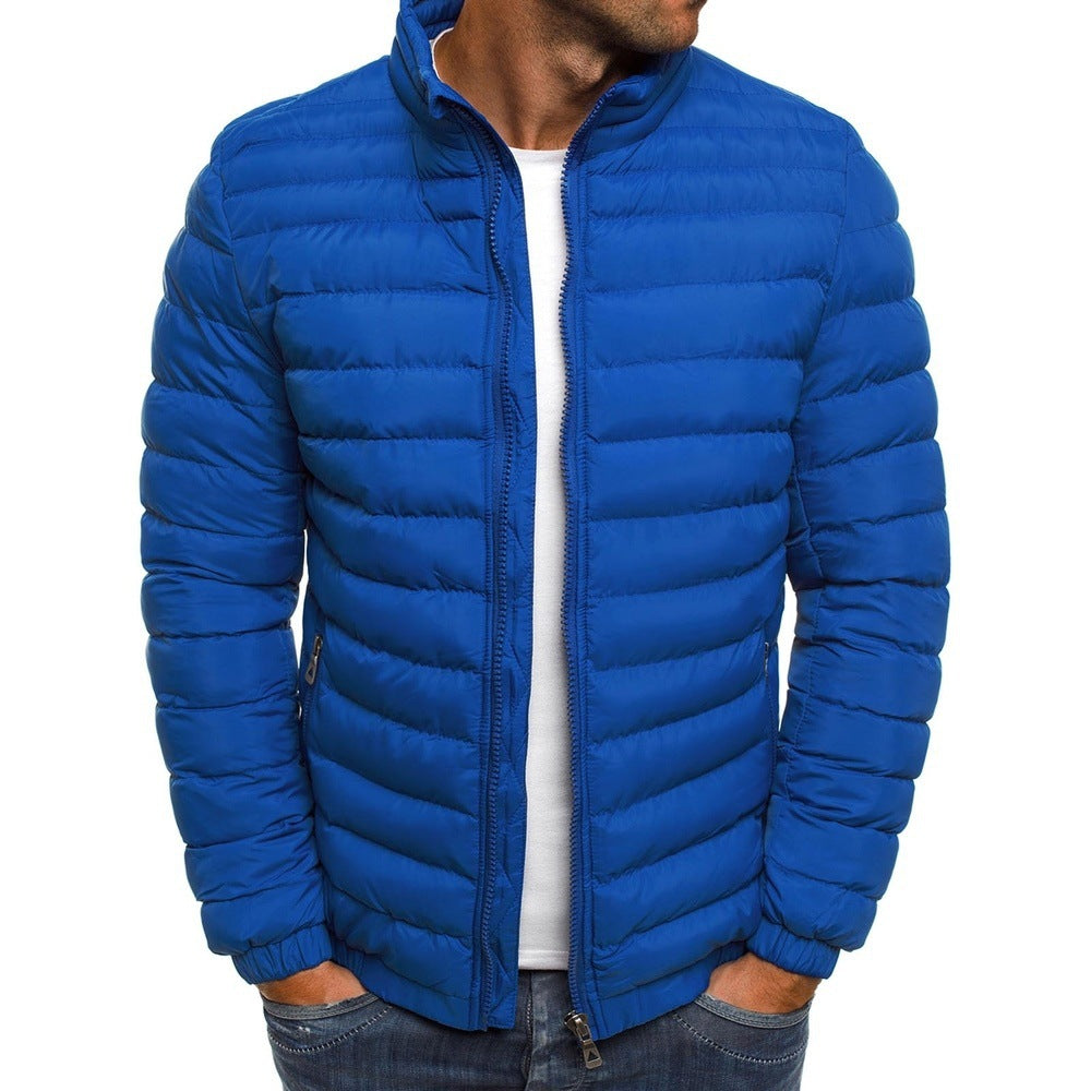 Homme portant une doudoune bleue matelassée, fermeture éclair, col montant, sur un t-shirt blanc. Mode masculine, veste hiver tendance.