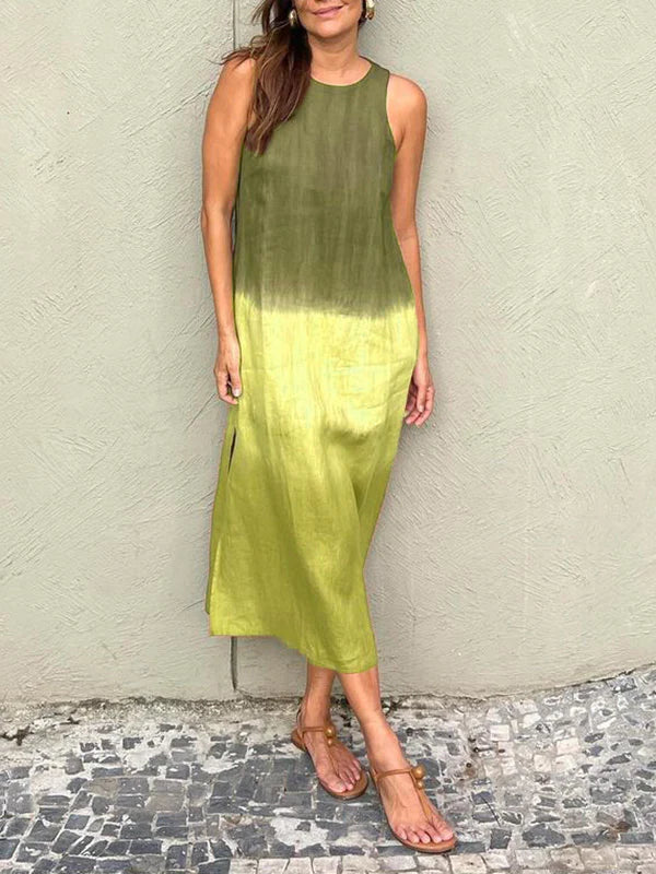 Robe longue dégradée vert olive, sans manches, portée par une femme, sur fond de mur texturé. Mode estivale, style décontracté, sandales plates.