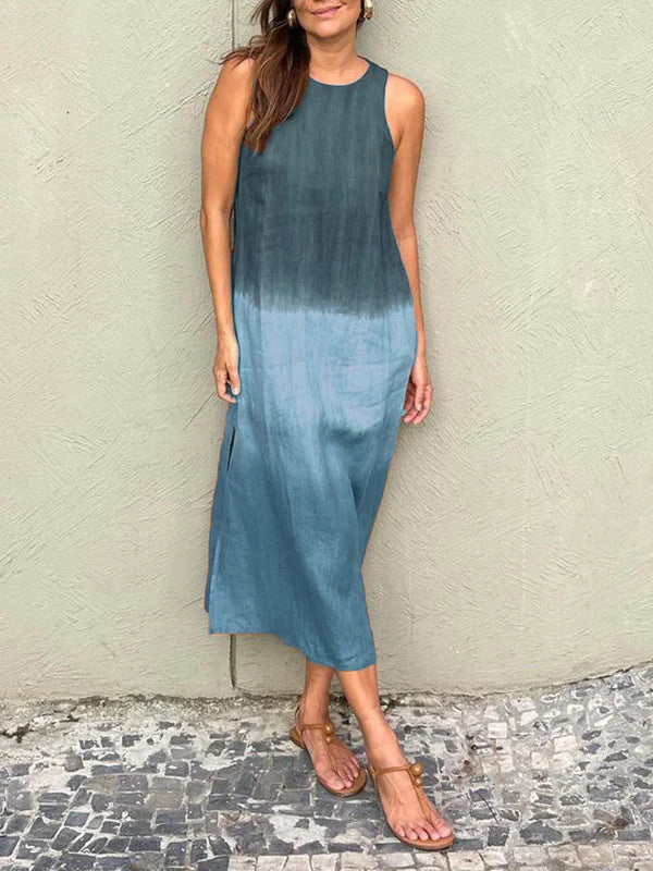 Robe longue dégradée bleue, sans manches, portée par une femme debout sur un sol en mosaïque. Mode estivale, style décontracté, tendance.