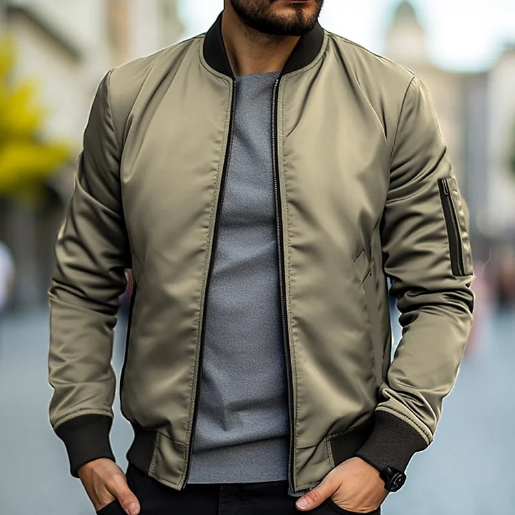 Homme portant un blouson bomber kaki, manches longues, col noir, sur un t-shirt gris, en ville. Mode masculine, style urbain, tendance automne.