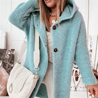 Femme portant un manteau en tricot bleu avec capuche, sac à main blanc, chemise à pois. Mode automne-hiver, style décontracté chic.