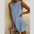 Robe d'été bleue en dentelle florale, sans manches, avec ourlet festonné, portée par une femme tenant un sac en osier. Mode féminine élégante.