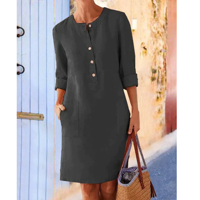 Robe droite noire à manches longues, boutons sur le devant, portée par une femme tenant un sac en osier. Mode féminine élégante et décontractée.