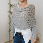 Femme portant un châle en tricot gris ajouré, style décontracté, sur un t-shirt blanc et un jean. Accessoire mode automne-hiver tendance.