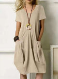 Robe beige ample avec poches, collier pendentif rond, femme blonde. Mode décontractée, style estival, tenue élégante et confortable.