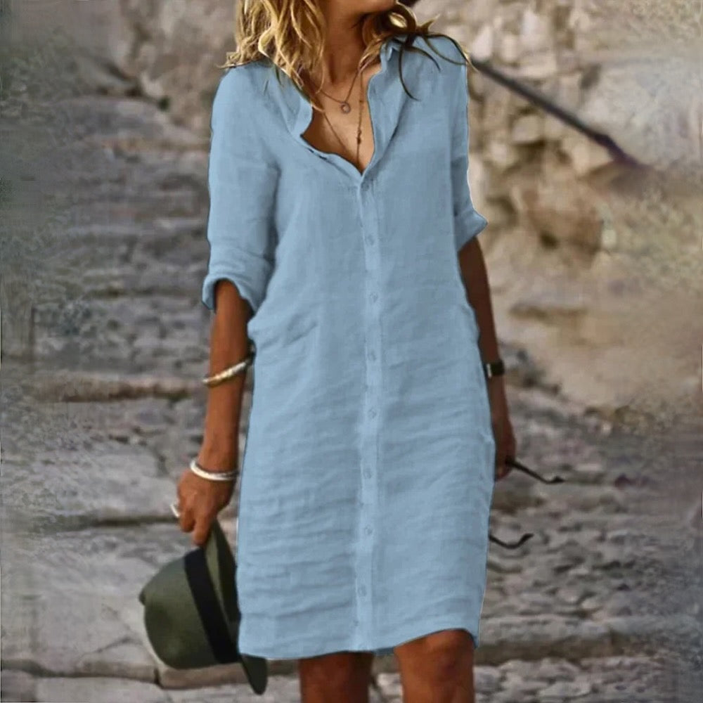 Robe en lin bleu clair pour femme, manches longues retroussées, col en V, style décontracté, idéale pour l'été, fond de rue pavée.