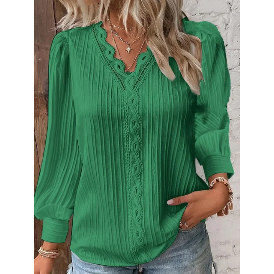 Blouse verte élégante à manches longues, col en V dentelé, portée par une femme blonde. Mode féminine chic, tenue décontractée tendance.