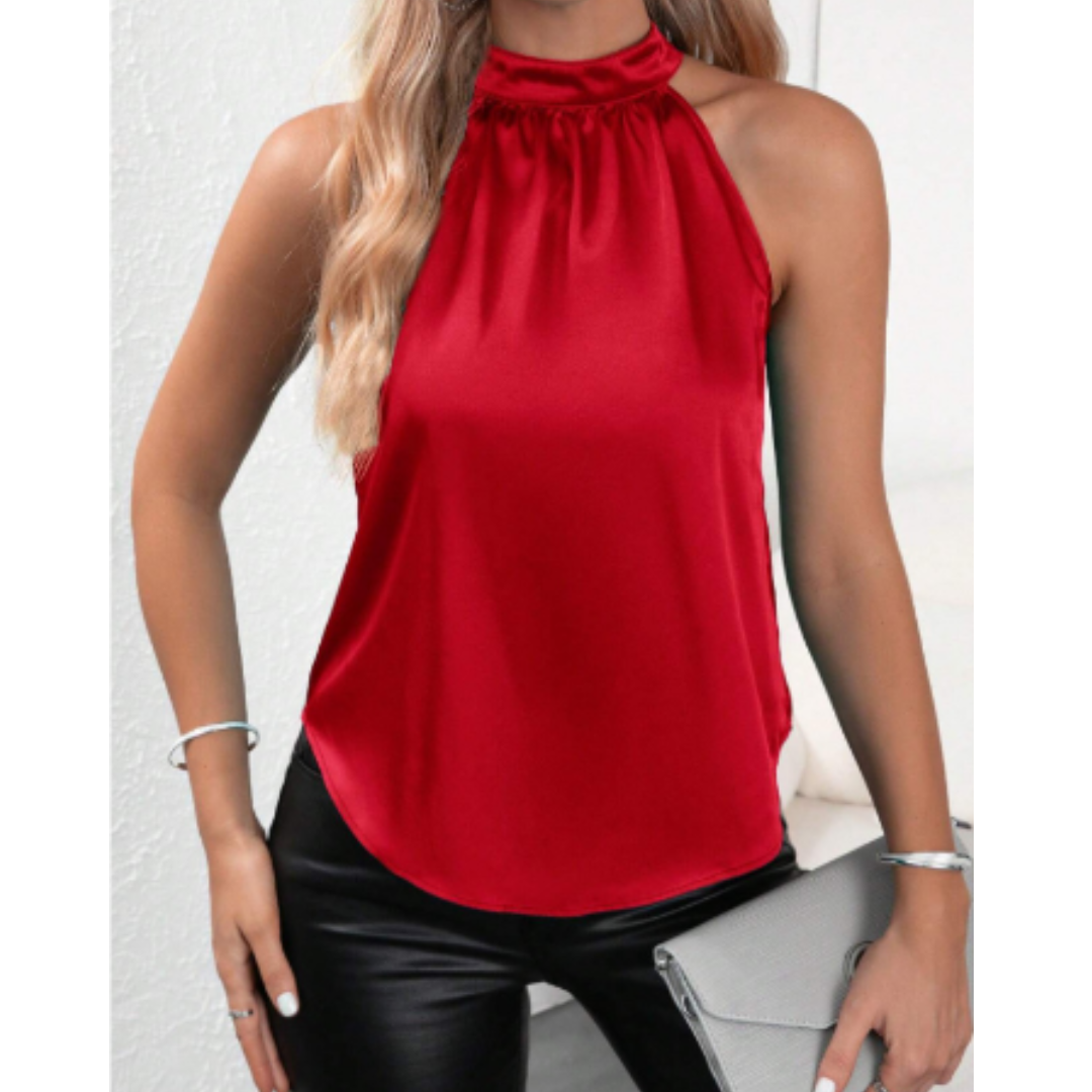 Femme portant un haut rouge sans manches en satin, col montant, avec un pantalon noir en cuir. Accessoires argentés et pochette grise.