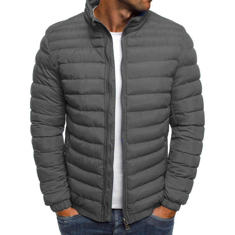 Homme portant une doudoune grise matelassée, fermeture éclair, col montant, poches latérales, style décontracté, mode hiver.