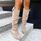 Bottes hautes en daim beige sur escaliers en pierre, mode automne, style décontracté, chaussures femme tendance, look urbain chic.