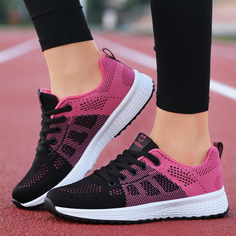 Chaussures de course noires et roses pour femmes sur piste d'athlétisme, design moderne, semelle blanche antidérapante, confort et style sportif.