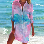 Robe de plage colorée avec motifs tourbillonnants rose et bleu, portée par une femme au bord de la mer. Mode estivale, tenue de plage élégante.