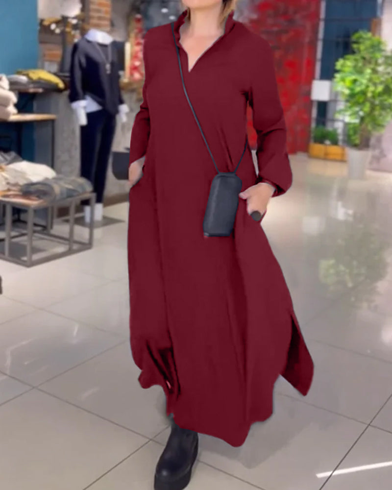 Robe longue bordeaux élégante portée par une femme dans une boutique moderne, accessoirisée d'un sac noir et de bottes, mode automne-hiver.