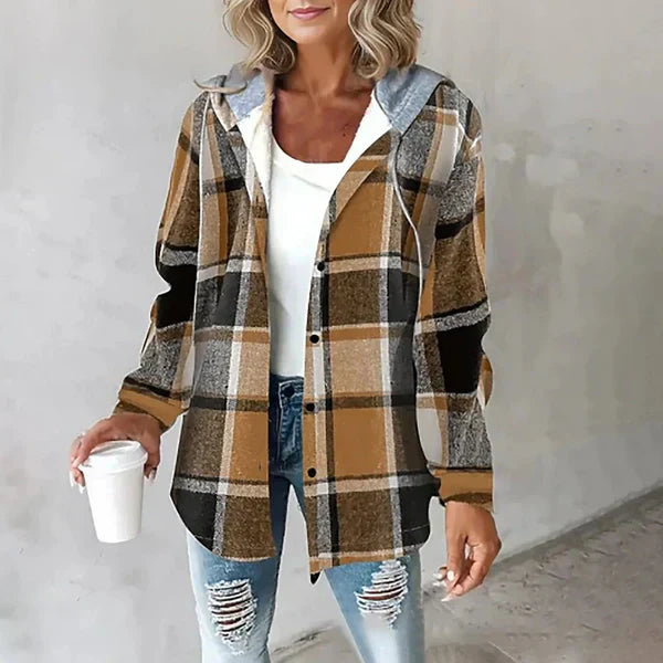 Femme portant une chemise à carreaux marron et noir, t-shirt blanc, jeans déchirés, tenant un gobelet blanc. Mode décontractée, tendance automne.