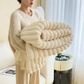 Femme tenant une couverture en fausse fourrure beige, douce et moelleuse, dans un salon moderne. Décoration intérieure élégante et confortable.