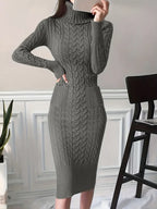 Robe pull gris en maille torsadée, manches longues, col roulé, portée par une femme. Style élégant et confortable pour l'hiver.