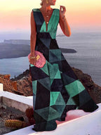 Robe longue géométrique verte et noire portée par une femme, avec vue sur mer au coucher du soleil. Mode élégante, style été, paysage côtier.