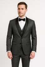 Homme en costume trois pièces gris foncé avec nœud papillon noir, chemise blanche. Mode masculine élégante, tenue de soirée formelle.