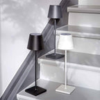 Trois lampes de table modernes en métal noir, gris et blanc sur des marches d'escalier, design minimaliste, éclairage intérieur élégant.