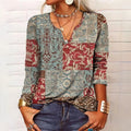 Femme portant un pull patchwork bohème à motifs floraux rouges et bleus, col en V, manches longues, accessoires dorés, style décontracté chic.
