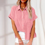 Femme portant une chemise rose en lin à manches courtes, col classique et boutons, associée à un pantalon blanc. Mode estivale élégante et décontractée.