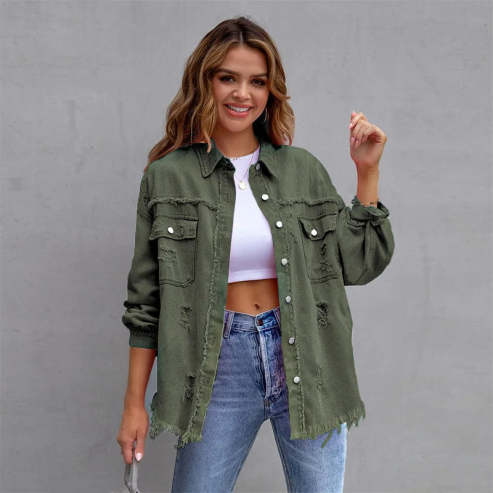 Femme souriante portant une veste en jean vert kaki, chemise blanche et jean bleu. Mode décontractée, tendance automne, style urbain.
