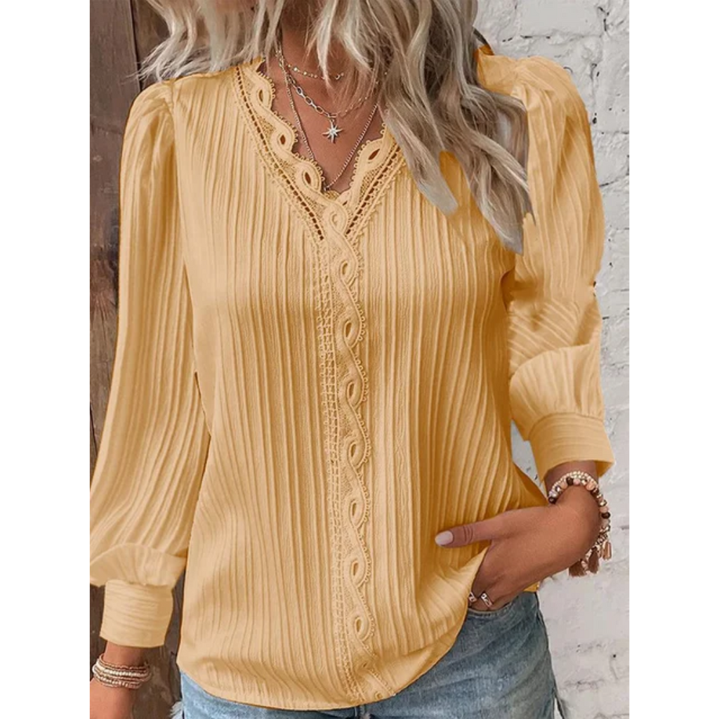 Blouse jaune à manches longues avec dentelle, portée par une femme aux cheveux blonds ondulés, associée à un collier étoile et un bracelet.