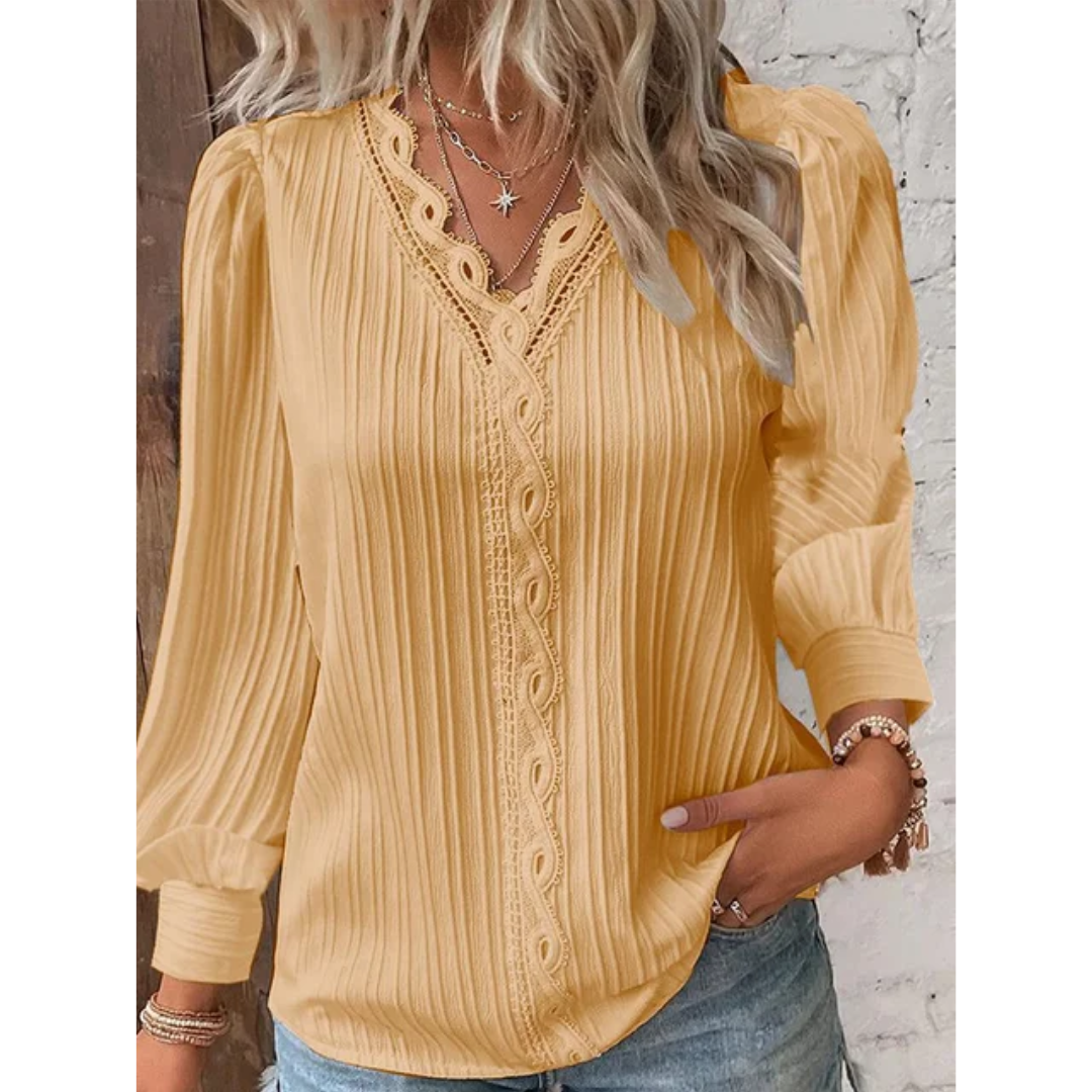 Blouse jaune à manches longues avec dentelle, portée par une femme aux cheveux blonds ondulés, associée à un collier étoile et un bracelet.