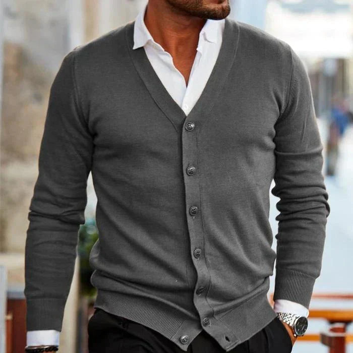 Homme portant un cardigan gris élégant sur chemise blanche, style décontracté chic, mode masculine automne, montre-bracelet argentée visible.