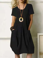 Robe noire élégante avec poches, collier pendentif ovale, manches courtes. Mode féminine chic, tenue décontractée, style moderne.
