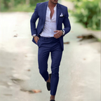 Homme élégant en costume bleu, chemise blanche, marchant en extérieur. Mode masculine, style chic, tenue formelle, tendance vestimentaire.