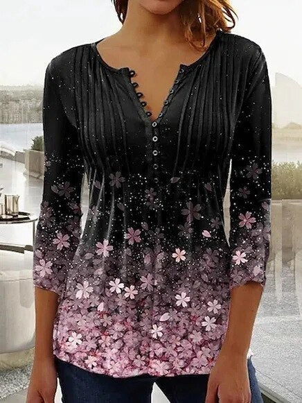 Femme portant un chemisier noir à manches trois-quarts avec motifs floraux roses et dégradé, col en V boutonné, style décontracté élégant.