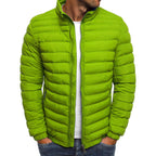 Homme portant une doudoune verte matelassée, col montant, sur un t-shirt blanc, style décontracté, mode automne-hiver, tendance vestimentaire.