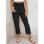 Pantalon noir femme taille haute, coupe ample, poches avant, ourlets retroussés, style décontracté, mode tendance, chaussures sandales beiges.
