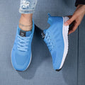Chaussures de sport bleues pour femme, design moderne, semelle blanche antidérapante, portées avec un jean déchiré. Idéales pour le fitness et la marche.