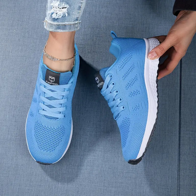 Chaussures de sport bleues pour femme, design moderne, semelle blanche antidérapante, portées avec un jean déchiré. Idéales pour le fitness et la marche.