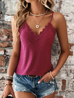 Femme en débardeur dentelle bordeaux et short en jean, posant devant un mur de briques. Mode estivale, tenue décontractée, accessoires tendance.