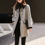Femme portant un manteau gris élégant, col noir, sac à bandoulière en cuir, tenue chic d'hiver, mode urbaine, style moderne et sophistiqué.