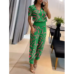 Femme portant une combinaison verte à motifs roses, posant devant un miroir. Mode élégante, tenue d'été, style décontracté chic.