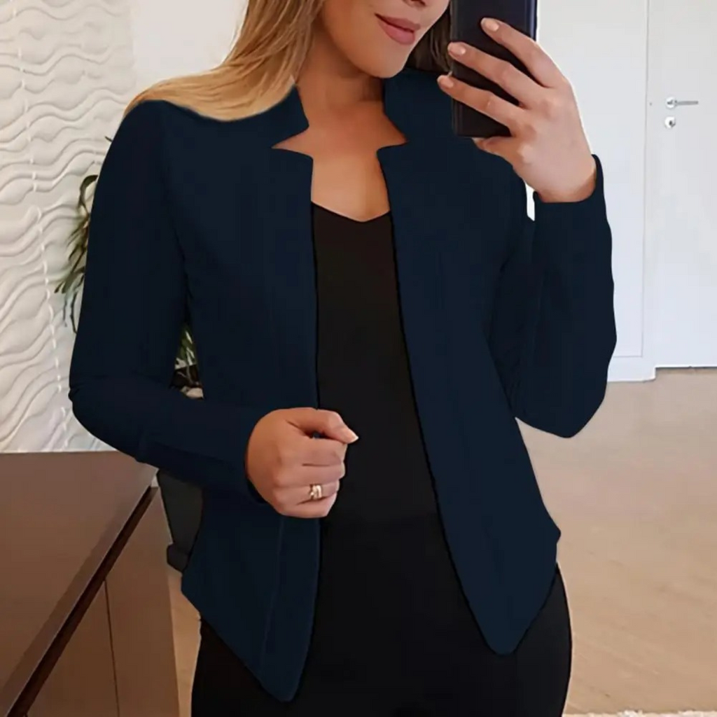 Femme en veste noire élégante prenant un selfie dans un intérieur moderne, tenue professionnelle, mode féminine, style chic et contemporain.