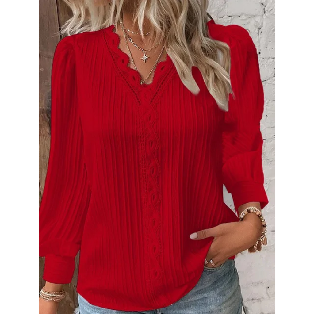 Femme portant un chemisier rouge à manches longues avec dentelle, col en V, colliers dorés, et jean décontracté. Mode féminine élégante.