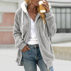 Femme portant un manteau en fausse fourrure gris, tenant un café à emporter. Mode décontractée, tendance automne, confort et style urbain.