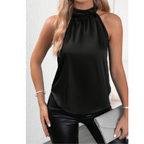 Femme portant un haut noir sans manches en satin, col montant, avec un pantalon en cuir noir et une pochette grise. Mode élégante et chic.
