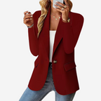 Femme en blazer rouge élégant, tenant un smartphone, portant un top blanc et un jean. Mode féminine chic, style décontracté moderne.
