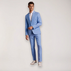 Homme en costume bleu clair élégant, chemise blanche, chaussures blanches, pose debout. Mode masculine, tenue formelle, style moderne.